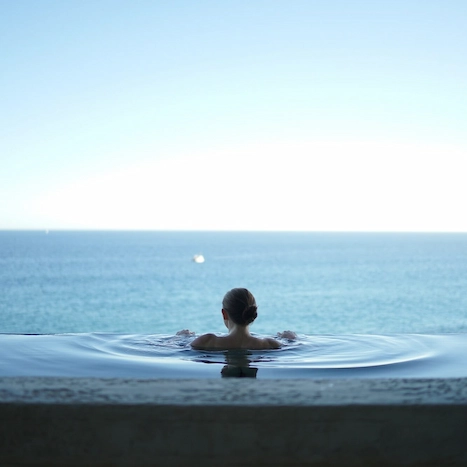 Lady in pool, savoring serene sea view, an escape to aquatic tranquility.