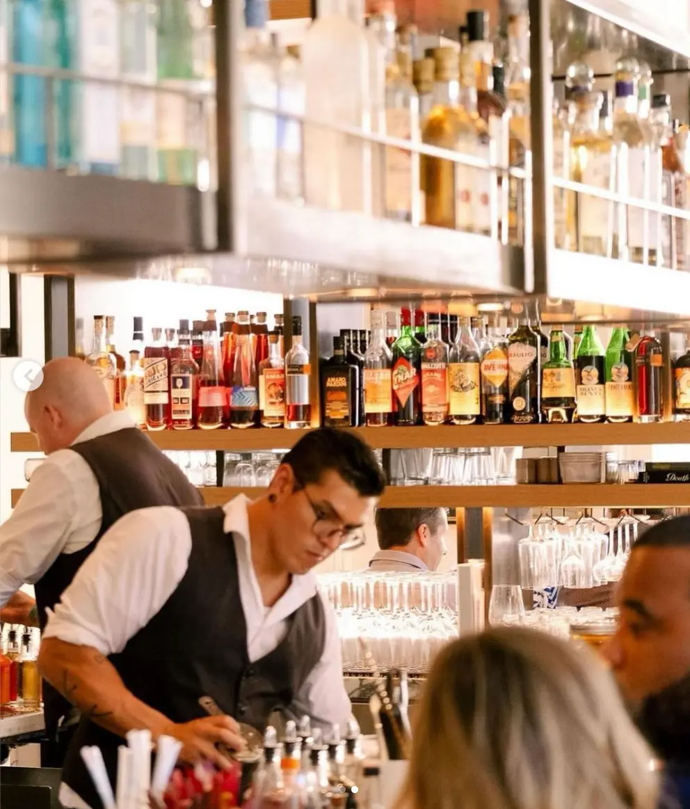 A bartender serving drinks at a restaurant bar.